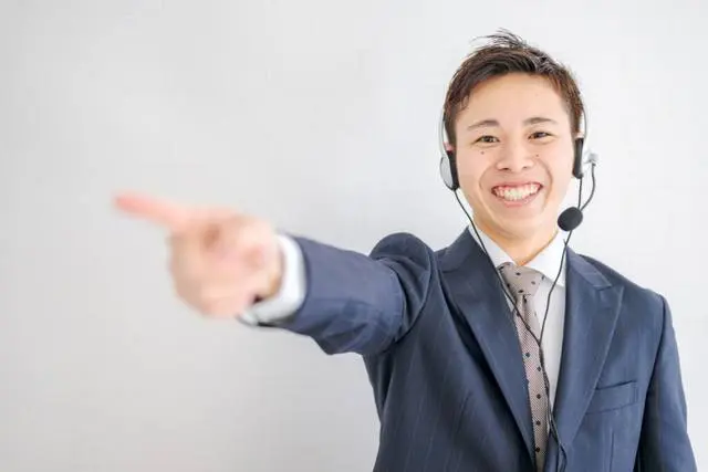 インカムをつけて笑顔で指さす男性