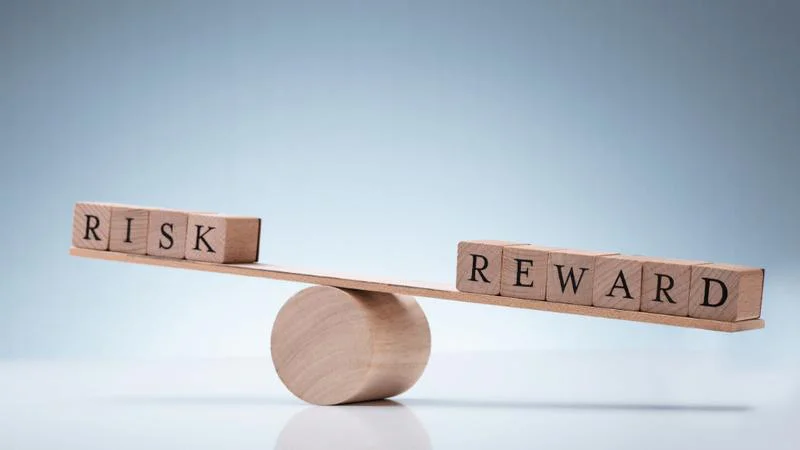 RISKとREWARDの積み木が載ったシーソー